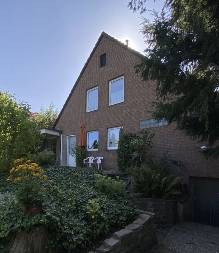 Außenansicht eines Klinkerhauses mit Garten, Terrasse und Treppenstufen.