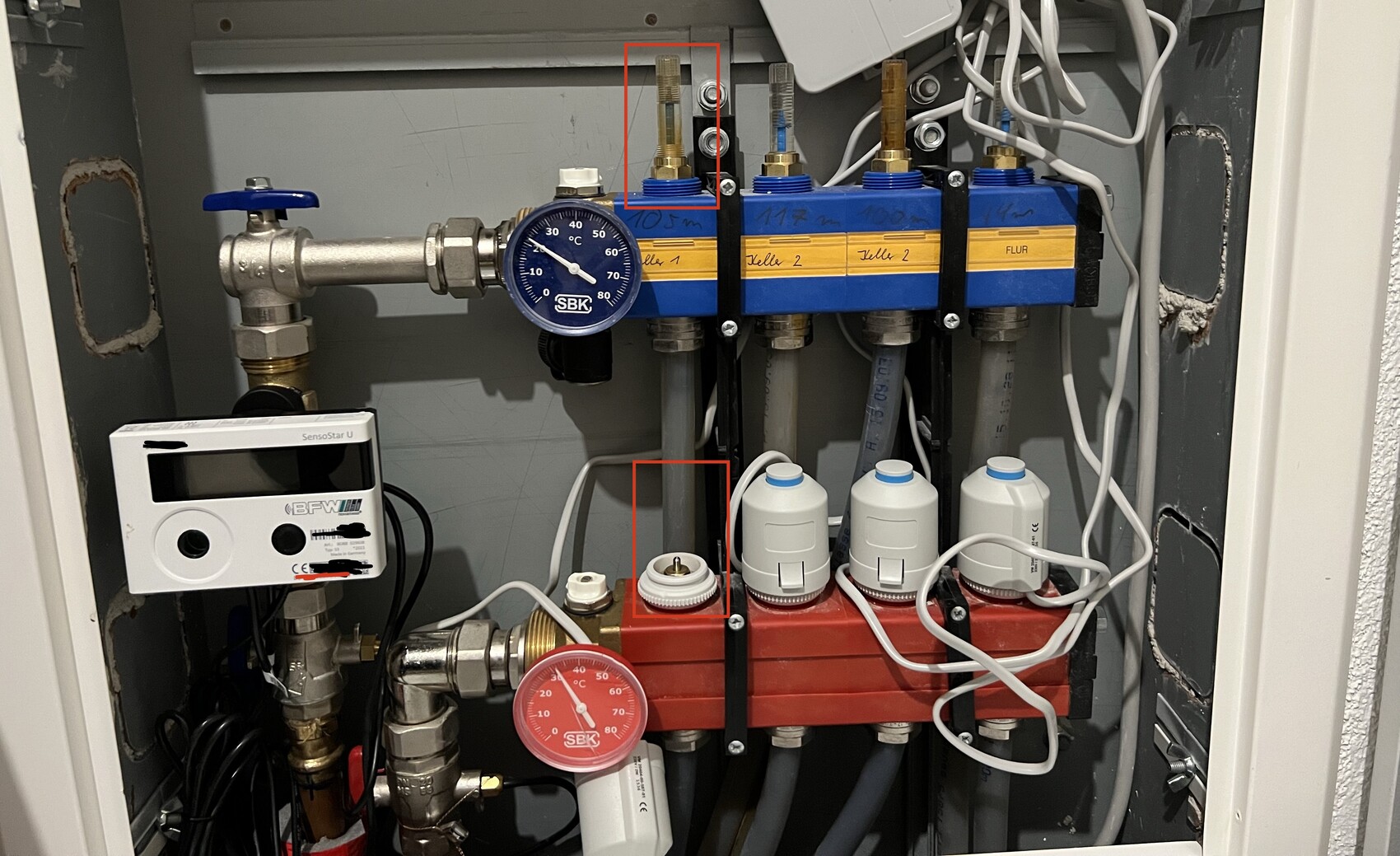 Heizungsverteiler mit Druckmessgerät, Absperrventilen, Pumpe und Kabeln.