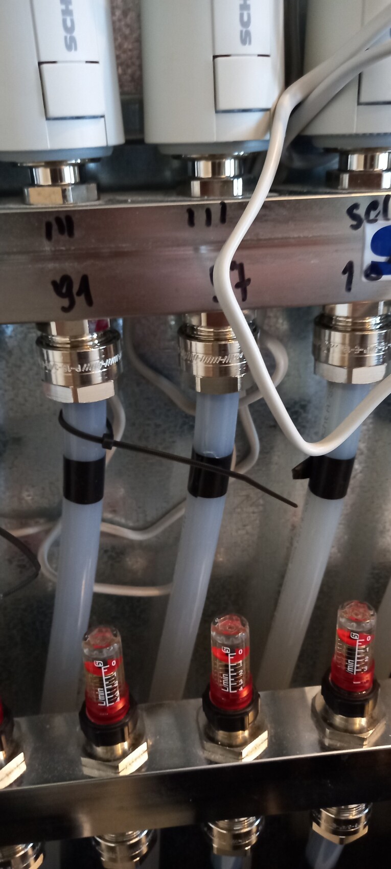 Pneumatischer Ventilblock mit blauen Schläuchen, weißen Steuereinheiten und roten Indikatoren.