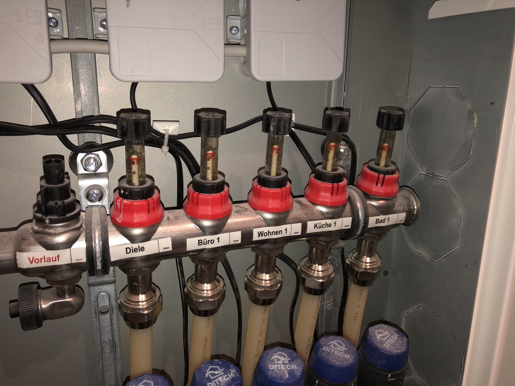 Hydraulik-Verteiler mit roten Ventilen; Beschriftung Vorlauf, Diele, Bad 1.