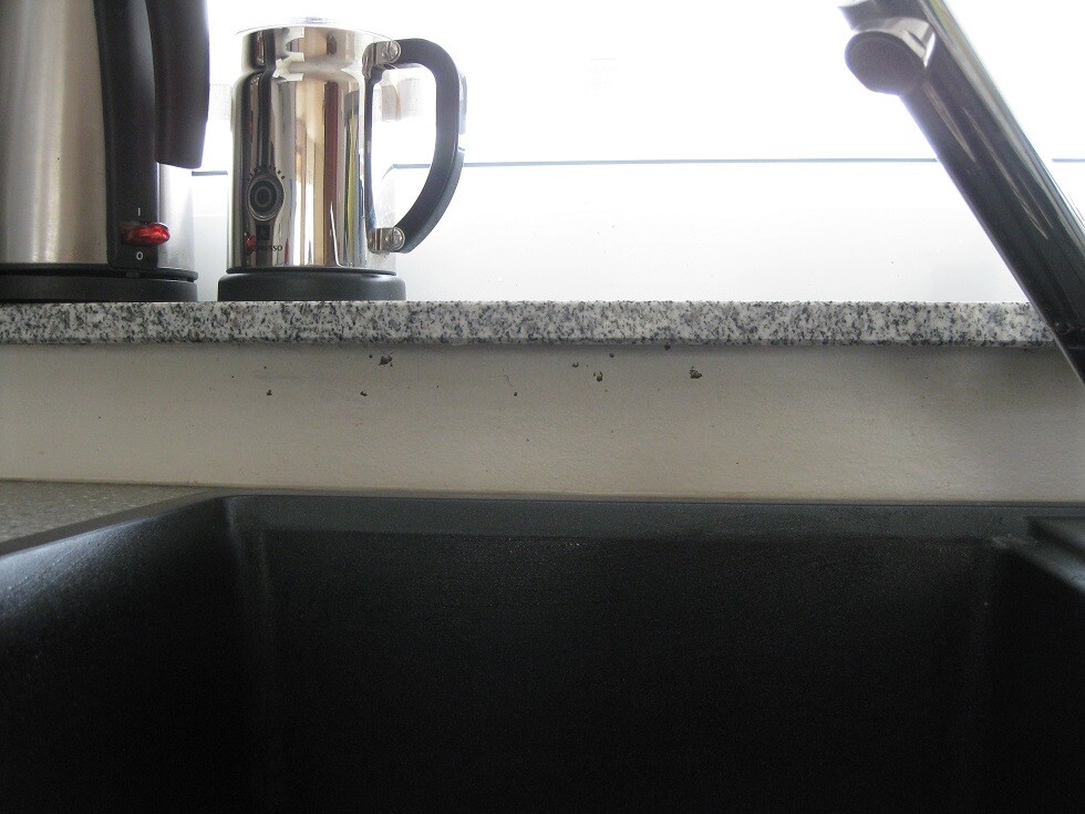 Küche mit Granit-Arbeitsplatte, Wasserhahn und Kessel auf der Fensterbank