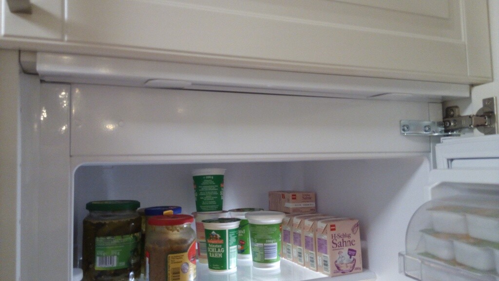 Offener Kühlschrank mit Gläsern, Joghurtbechern und Milchprodukten im Innenfach.