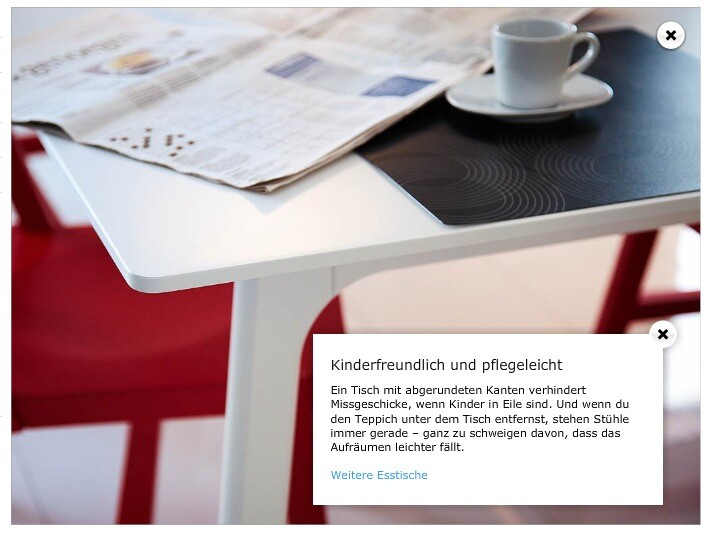 Weißer Tisch mit Zeitung und Kaffeetasse, rote Stühle im Hintergrund.