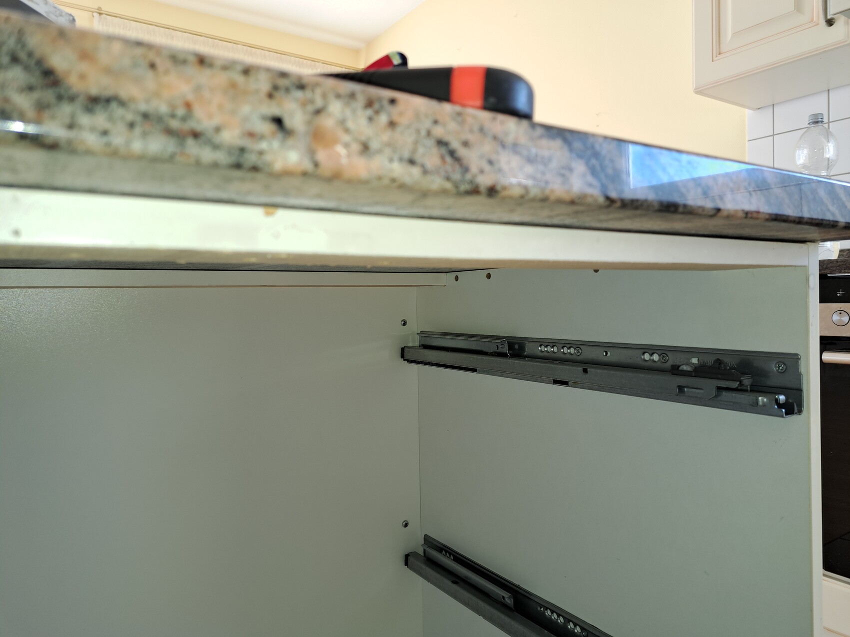 Unterseite einer Küchenarbeitsplatte über einem Schrank mit sichtbaren Schubladenführungen.