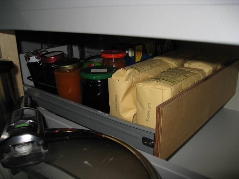 Aufgeschobene Küchenschublade mit Marmeladengläsern, Dosen und Vorratsverpackungen.