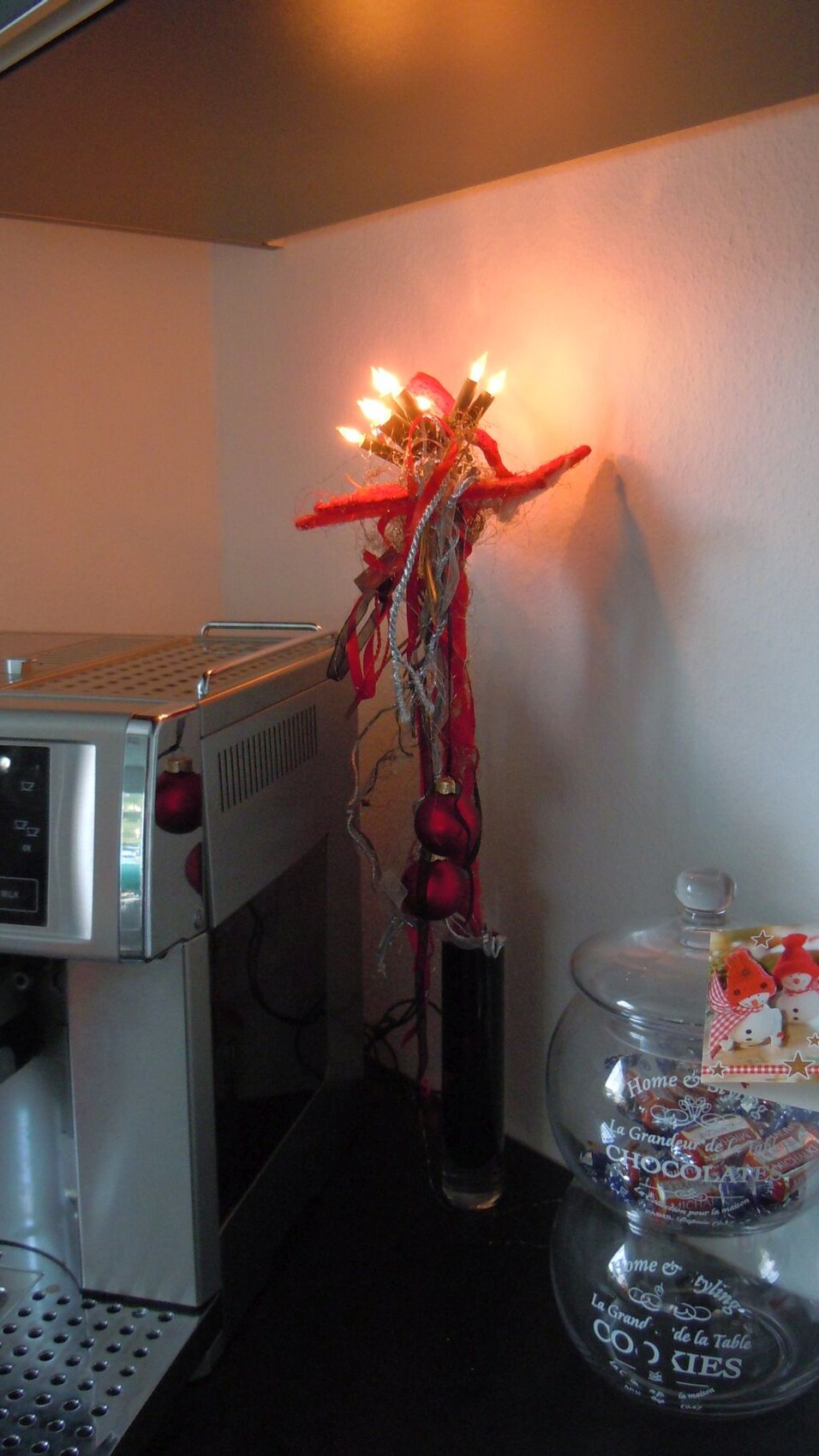 Küche mit Kaffeemaschine und weihnachtlicher Kerzen-Deko aus roten Bändern
