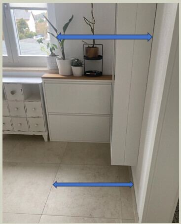 Heller Küchenbereich mit weißen Schränken, Fensterpflanzen und Fliesenboden