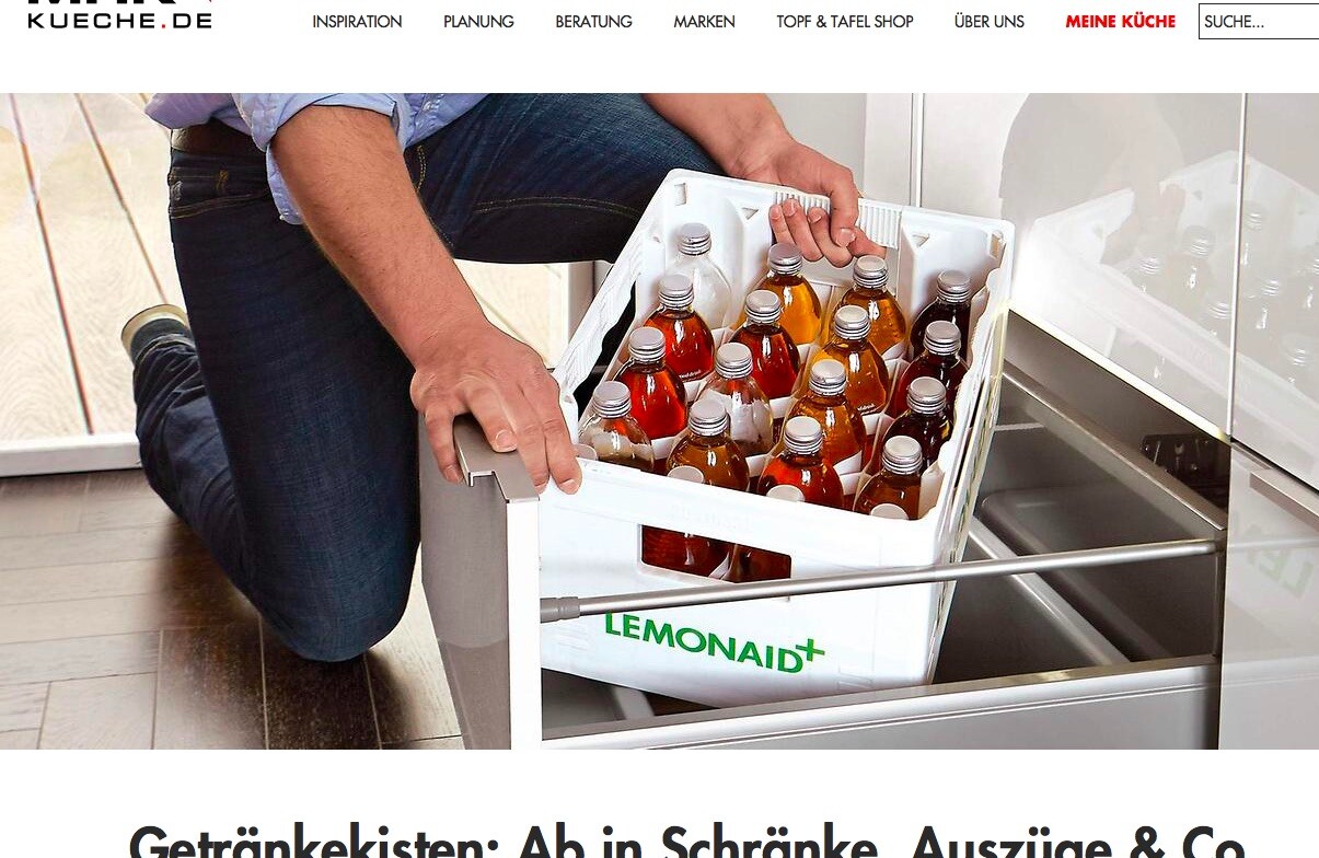 Person kniet in der Küche und zieht eine Getränkekiste aus dem Küchenschrank