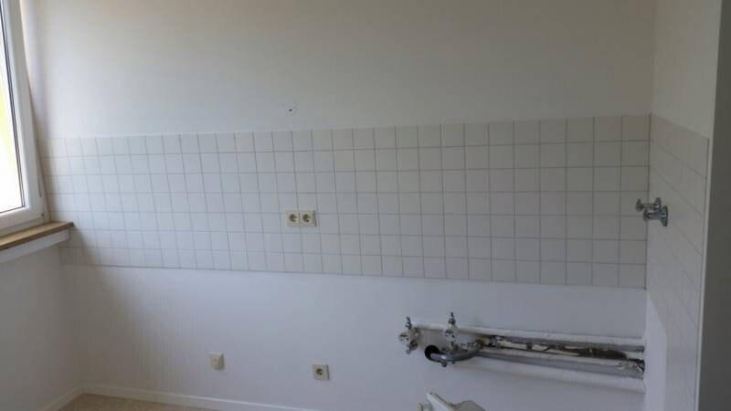 Küche im Renovierungszustand mit Wandfliesen, freiliegenden Rohren und Fenster