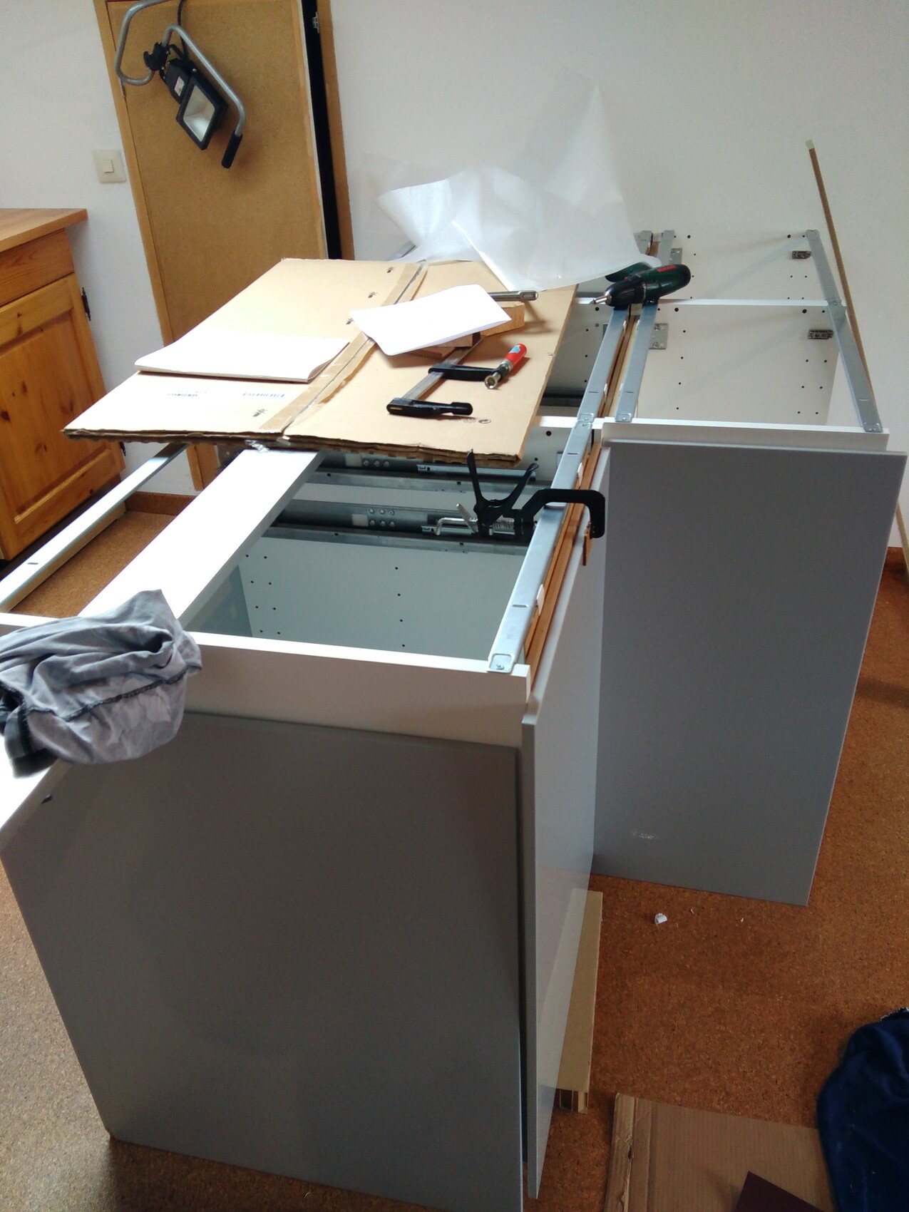 Küchenunterschrank im Aufbau mit Werkzeugen und Karton auf Arbeitsplatte