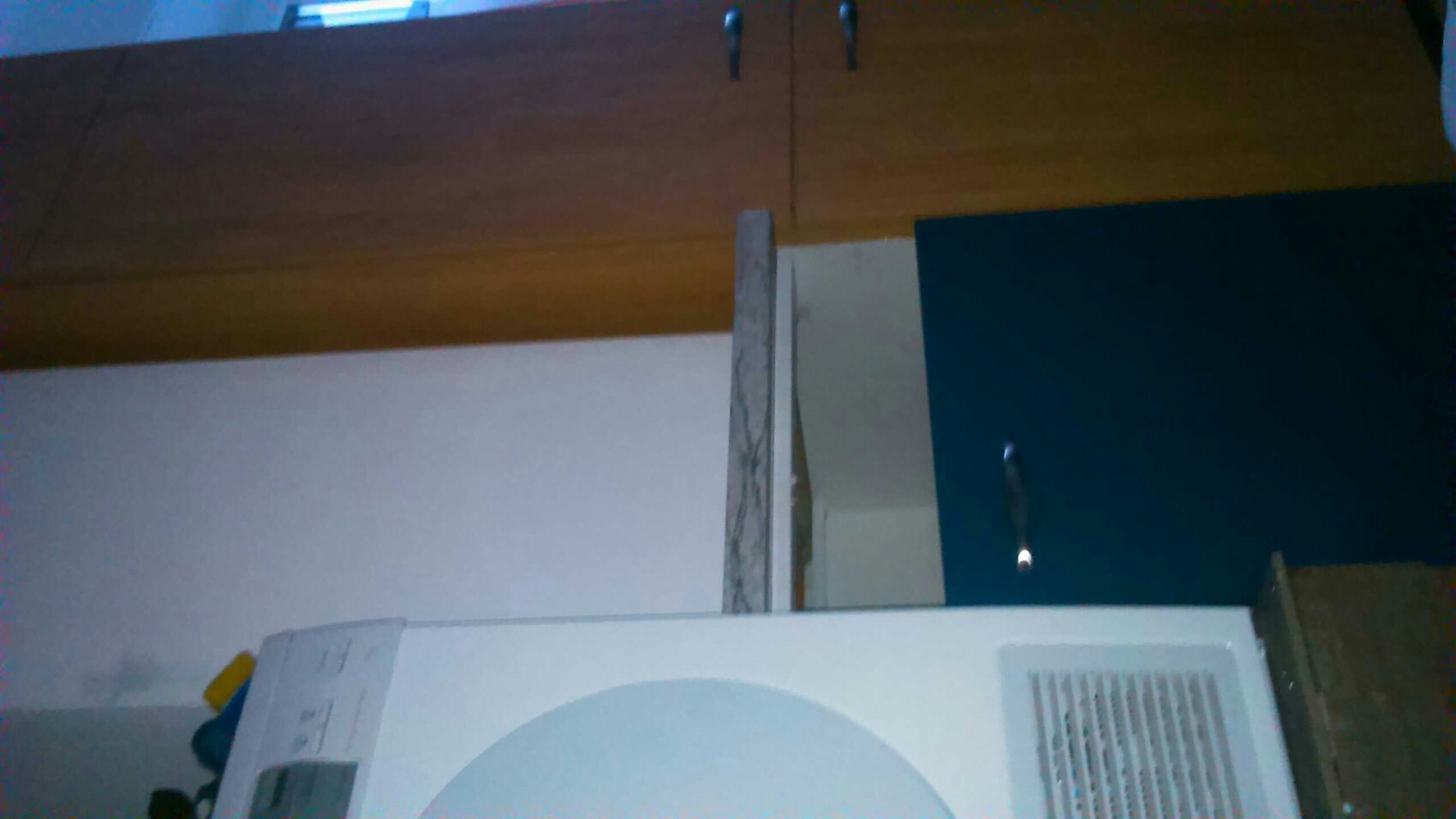 Küchenbereich mit blauer Schrankfront, weißen Geräten und Arbeitsplatte in Holzoptik