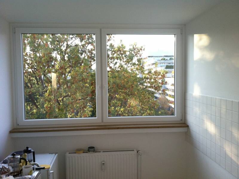 Küche mit großem Fenster, Fliesenwand, Heizkörper und kleine Küchengeräte auf Ablage