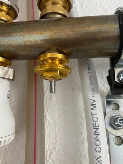 Unteres Rohrsystem mit Messingventil am Kupferrohr, weiße Leitung und Elektrobereich im Hintergrund.