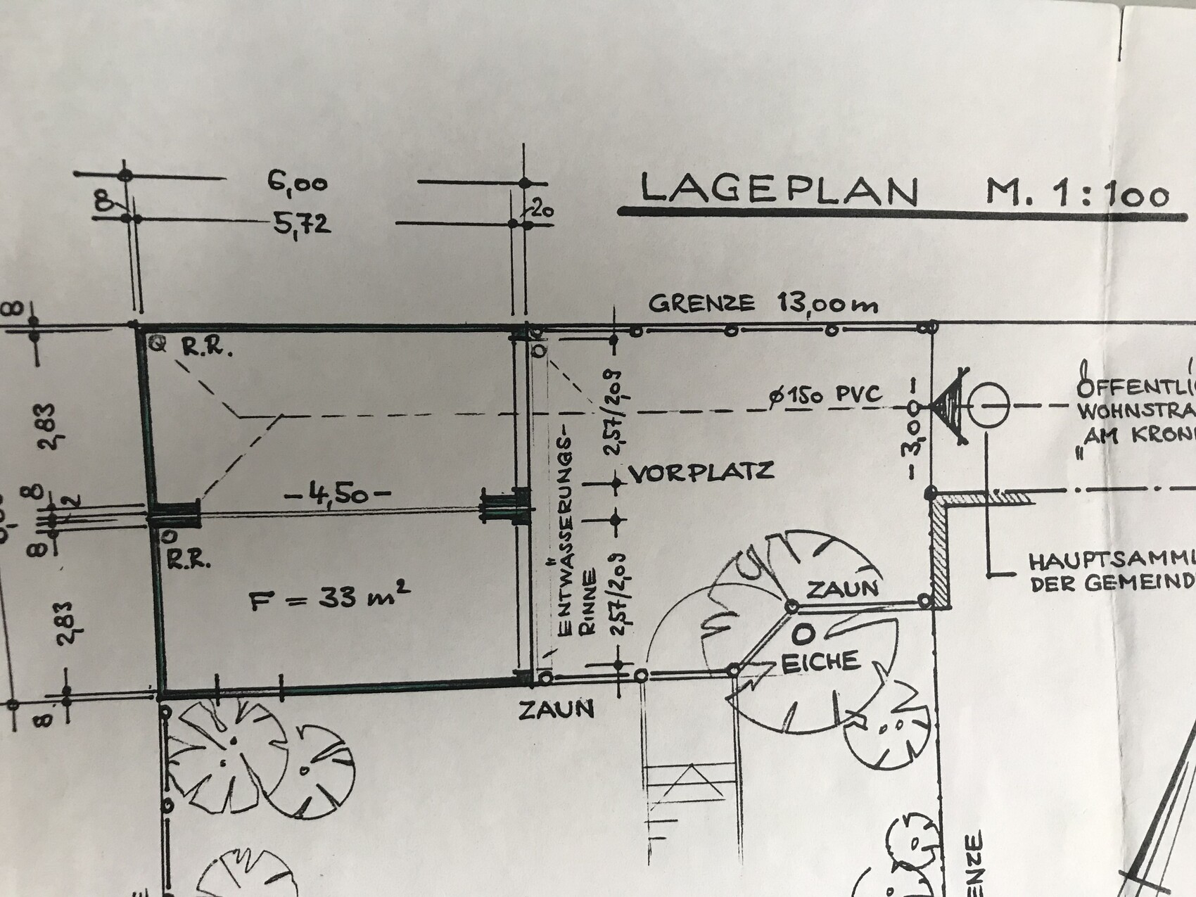 Lageplan eines Grundstücks im Maßstab 1:100 mit Zaun, Eiche und Grenzlinie.