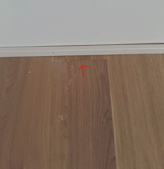 Kleiner Spalt zwischen Laminatbodenplatten nahe der Sockelleiste sichtbar.