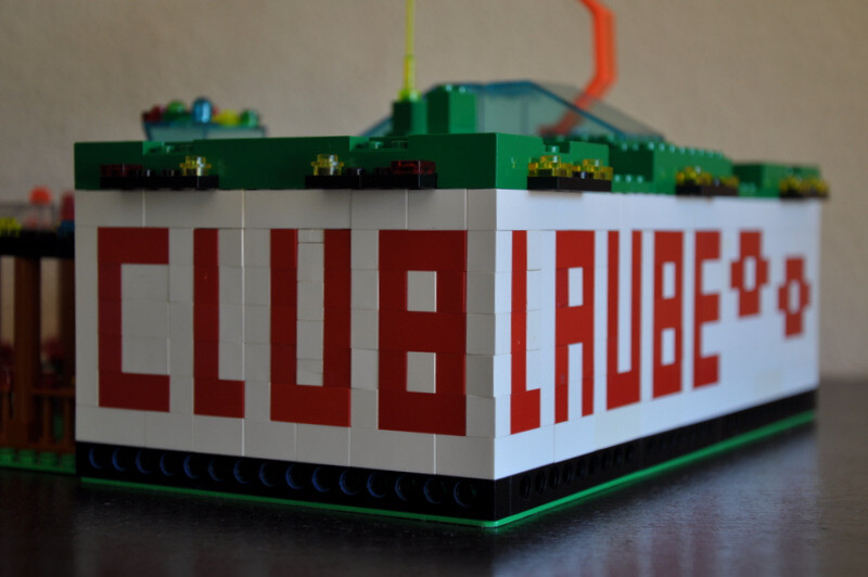 Lego-Hausmodell aus bunten Bausteinen mit rotem CLUB LEGO-Schriftzug an der Seite