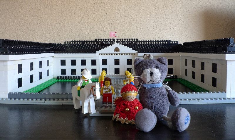 LEGO-Hausmodell mit weissen Fassaden, dunklem Dach, Hof und Plueschtier