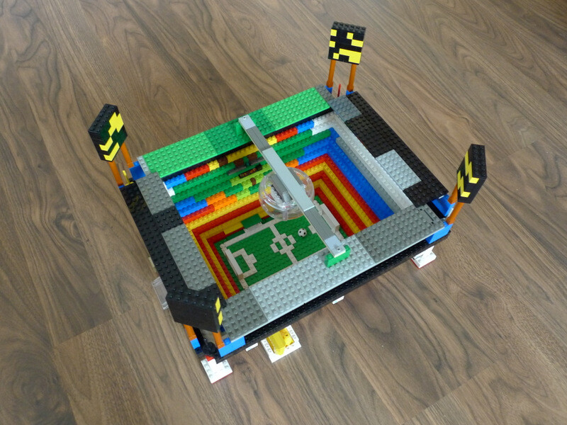 Ein Lego-Stadionmodell mit bunten Sitzreihen und kleinem Fußballfeld