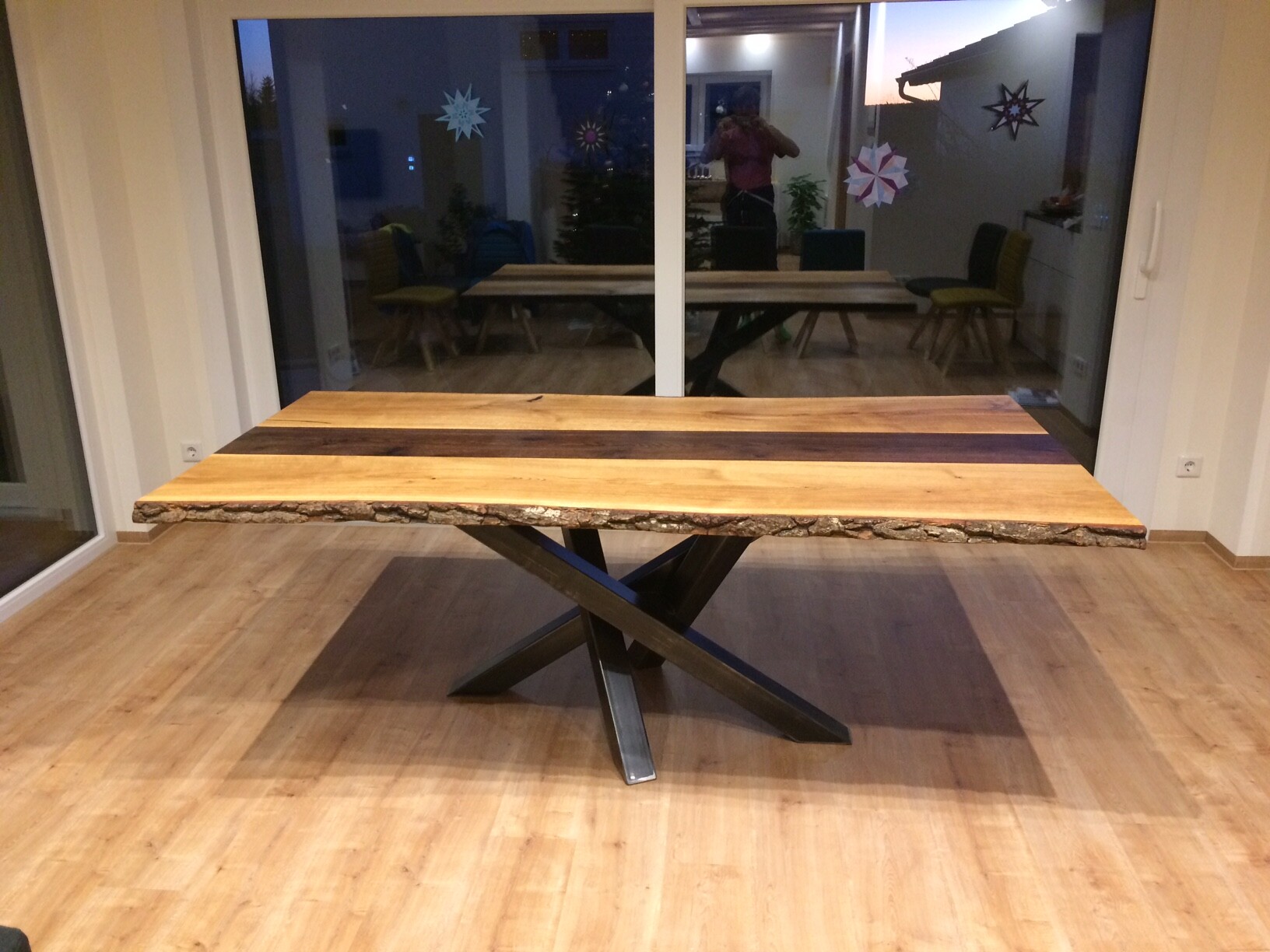 Großer Holztisch mit Naturkante (Baumstammkante) und schwarzem X-Gestell im Wohnzimmer.