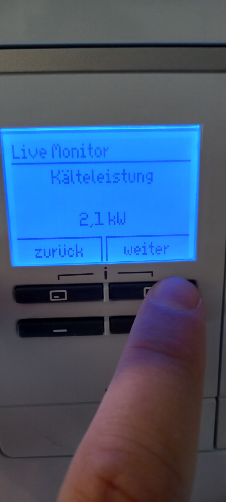 Blau beleuchtetes Bedienfeld mit Live Monitor, Kälteleistung 2,1 kW; Finger drückt Weiter.