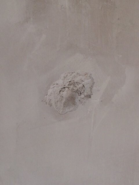 Grobe Wand mit unregelmäßigem Loch in der Putzoberfläche, Bauzustand