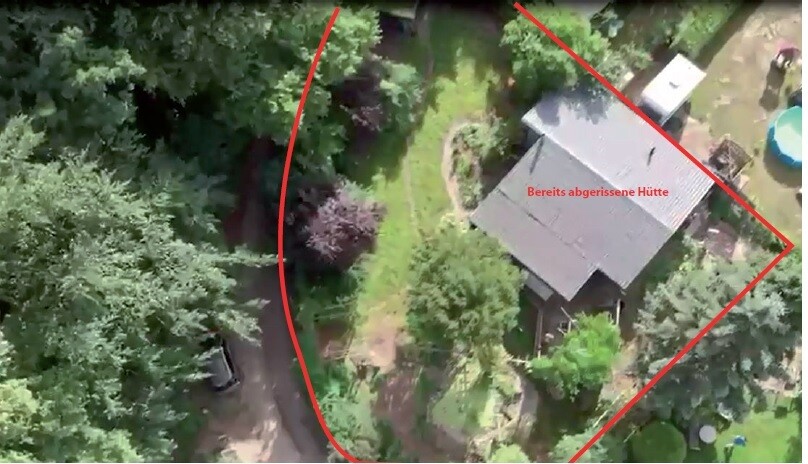 Luftaufnahme eines Grundstücks mit rotem Umriss, Haus und abgerissener Hütte im Wald