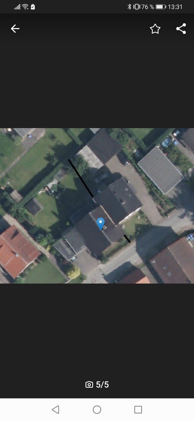 Luftbild eines Wohnviertels mit Gärten, Straßen und Häusern; blauer Marker auf einem Haus.