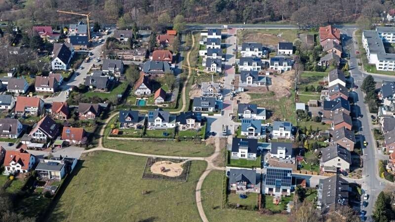 Luftbild eines Vororts mit Wohnhäusern, Straßen, Park mit Rundweg und Spielplatz