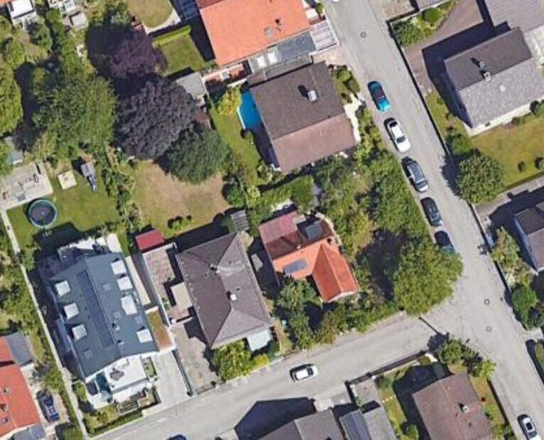 Luftaufnahme eines Wohnviertels mit Häusern, Straßen, Autos und Gärten.