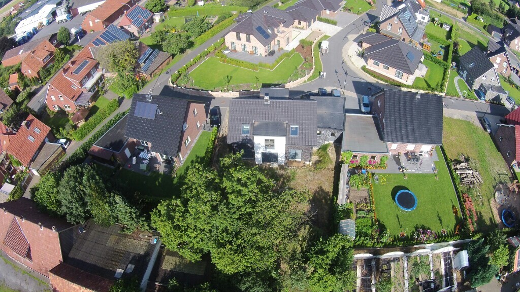Luftaufnahme eines Wohnviertels mit Häusern, Gärten, Hecken und rundem blauem Pool im Garten