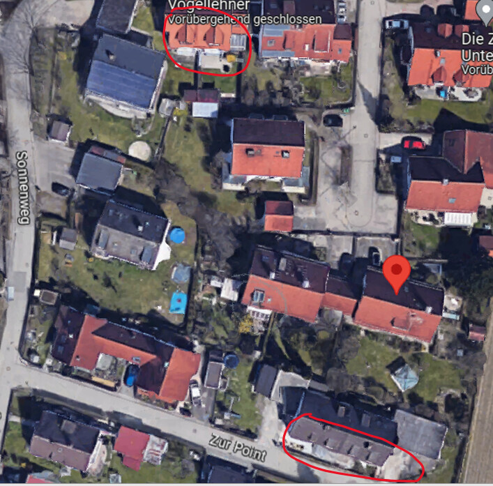 Satellitenbild eines Wohnviertels mit rotem Pin auf einem Wohnhaus; zwei Kreise markieren Bereiche.