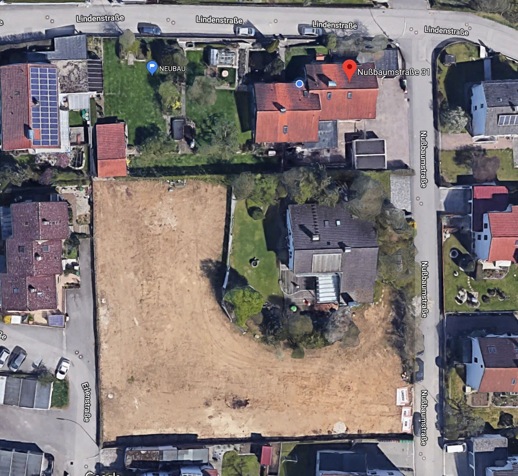 Luftbild zeigt rotes Einfamilienhaus neben groesser Bauflaeche