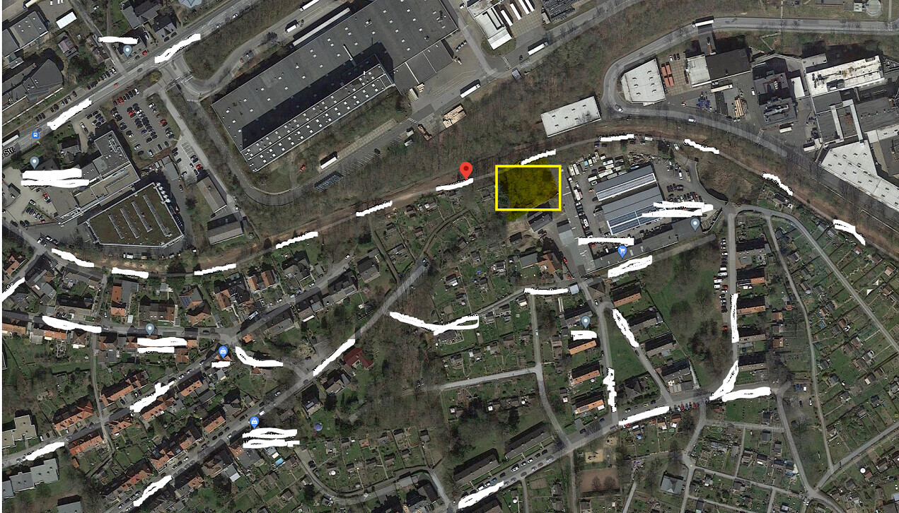 Satellitenansicht einer Stadt; gelbes Rechteck markiert Gebäude, roter Pin markiert Standort.