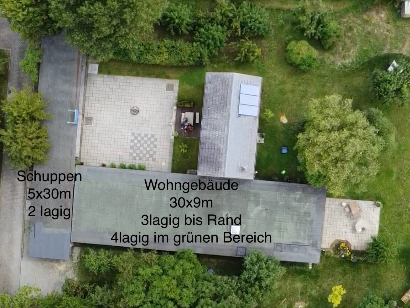 Drohnenaufnahme eines Gebäudekomplexes: Schuppen links, Wohngebäude rechts, Gartenbereich.