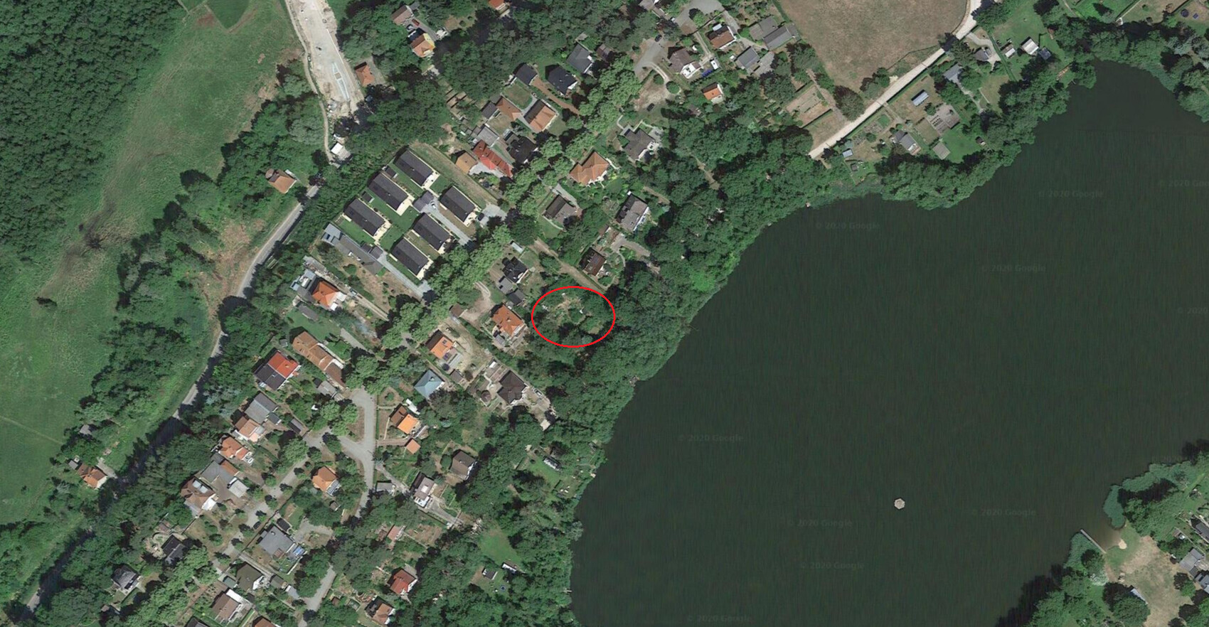 Luftaufnahme eines Wohnviertels am Seeufer; rote Markierung hebt ein Haus nahe dem Wasser hervor.