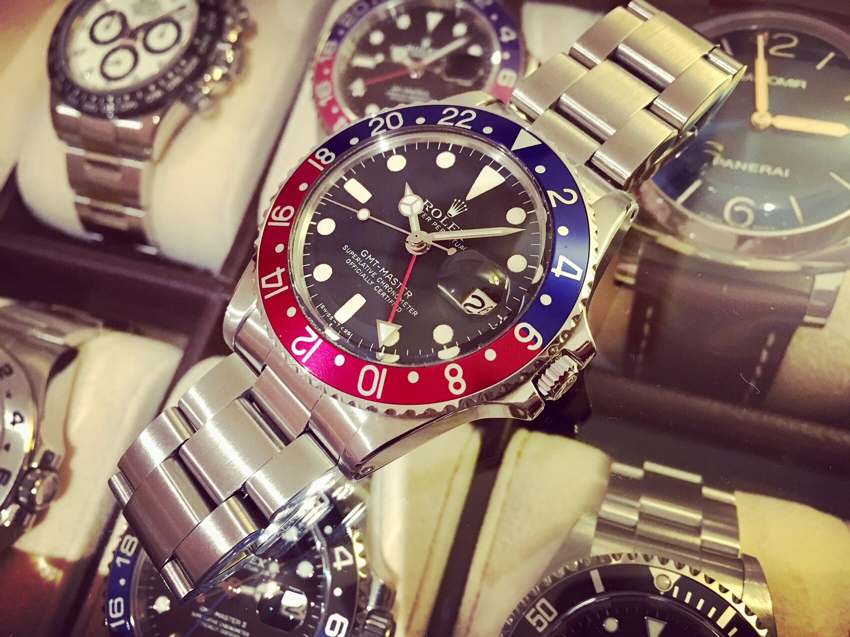 Mehrere Armbanduhren aus Metall; Hauptfokus eine Rolex GMT-Master mit roter/blauer Lünette.