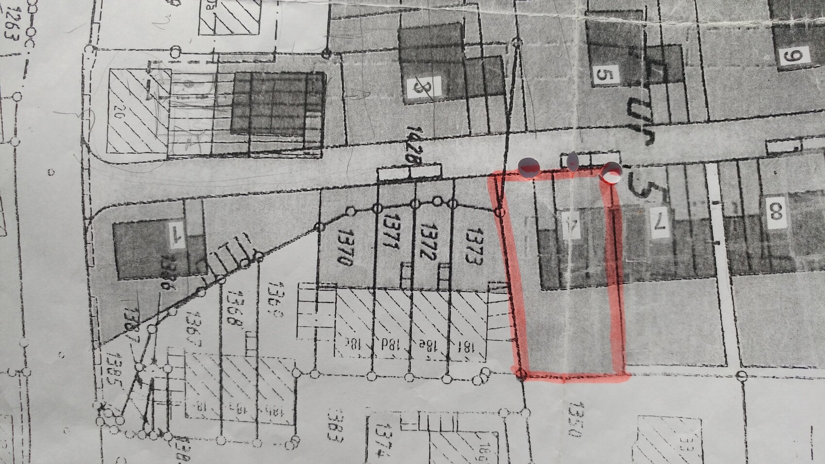 Schwarz-weiß Bauplan mit roter Umrandung eines Grundstücks entlang der Straße.