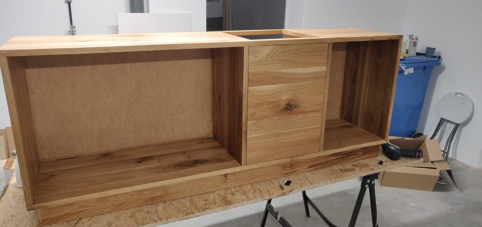 Holzsideboard aus Eiche mit drei Fächern auf Werkbank; linkes und rechtes Fach offen.