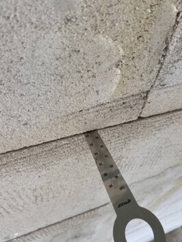 Nahaufnahme eines Betonblocks mit Messwerkzeug zur Rissmessung im Rohbau