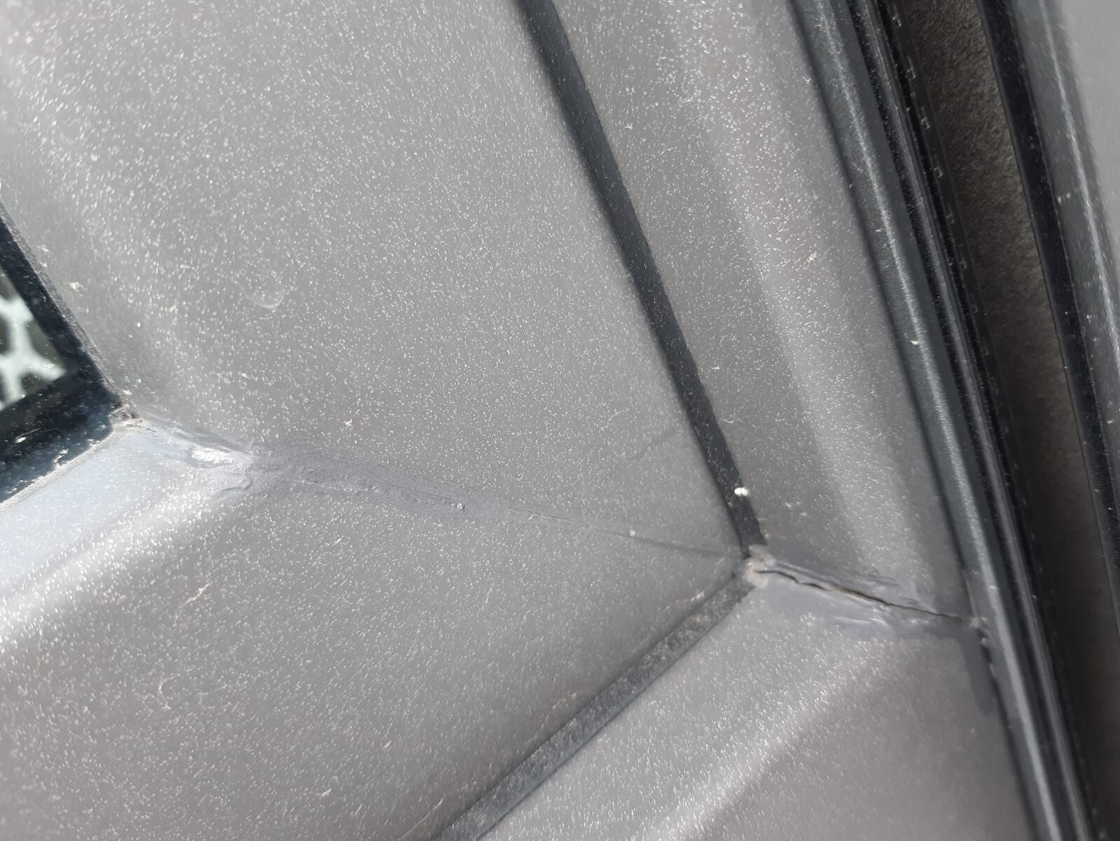 Nahaufnahme einer Metall-Dachkante mit Fuge und Dichtungsmaterial in der Ecke.