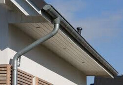 Dachrinne mit Downspout am weißen Hausdach, Traufe sichtbar