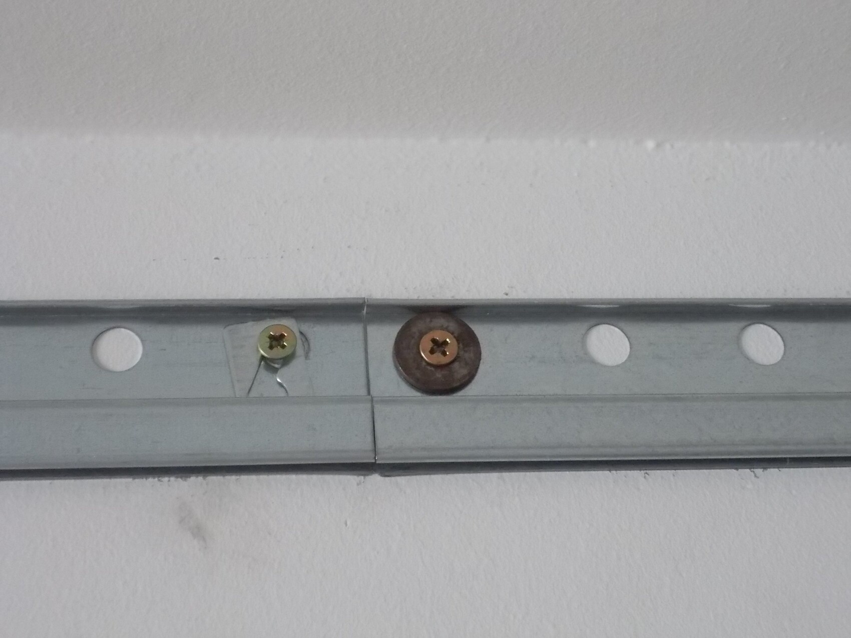 Metall-Montageschienensystem mit Schrauben an einer weißen Wand
