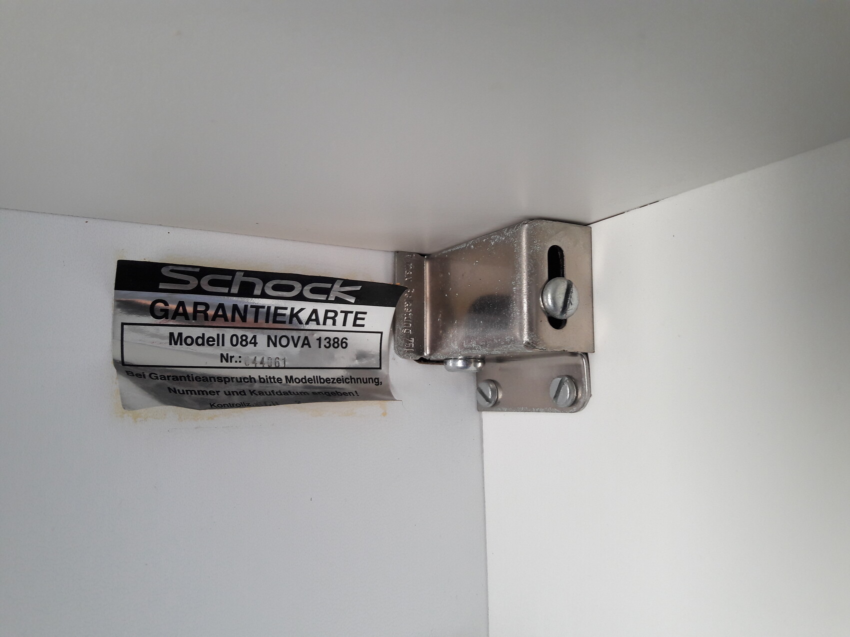 Nahaufnahme eines Metall-Scharniers mit Garantiekarte an einer Tür.