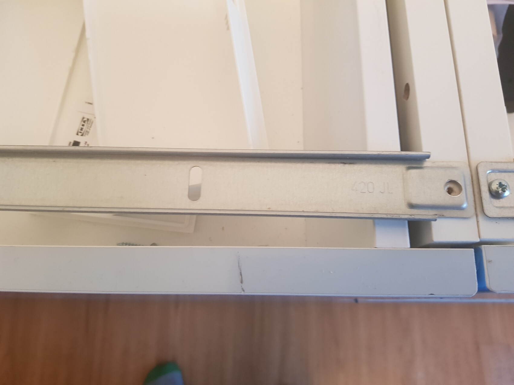 Nahaufnahme eines Metall-Schubladenführers mit Bohrungen und Schraubenteil.