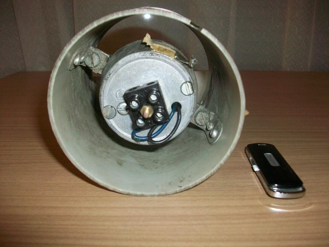 Metallische Deckenlampe mit Drahtverbindungen liegt auf einem Holztisch.