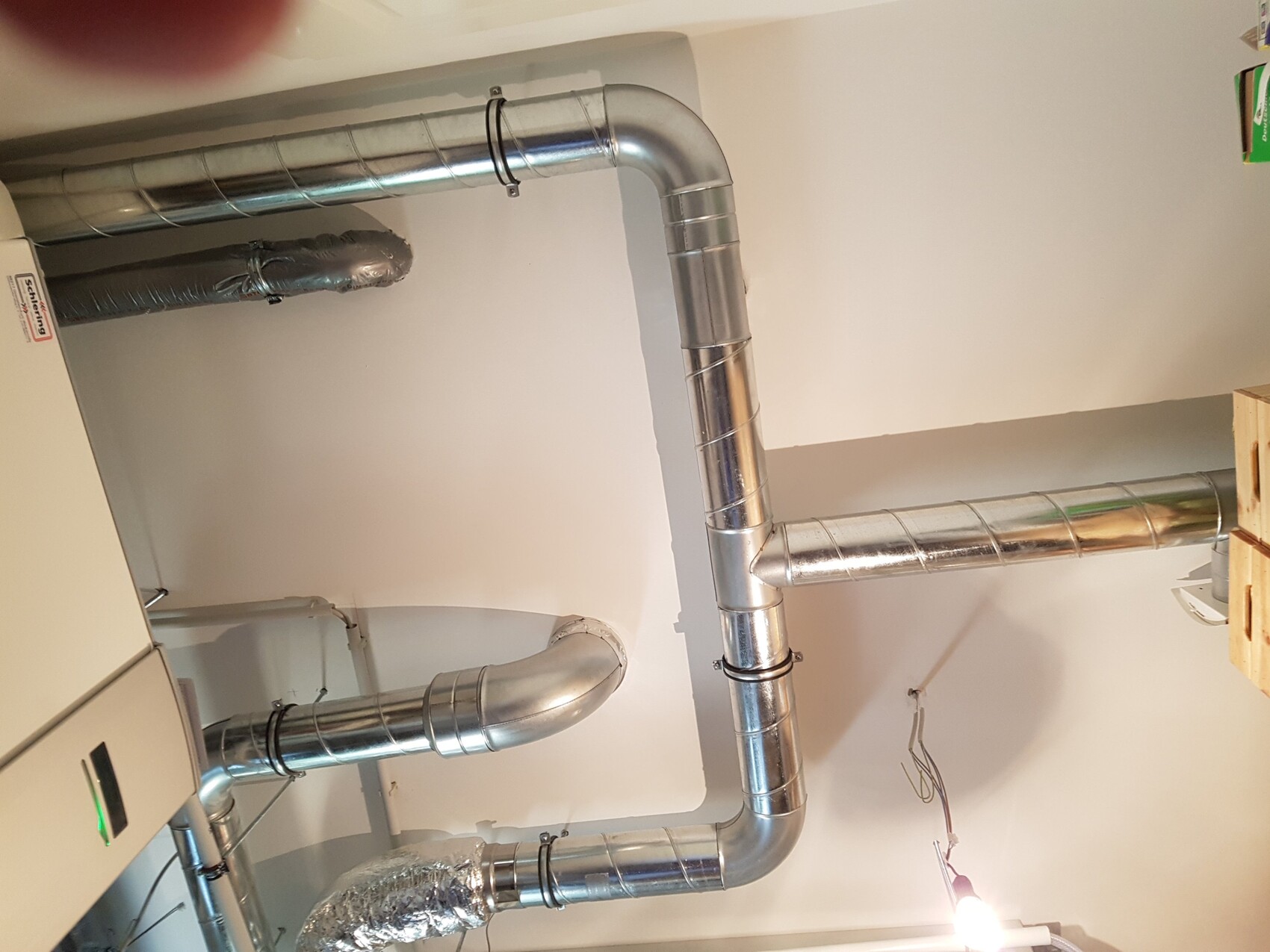 Metallische Lüftungsrohre und Rohrleitungen im Haustechnikraum.