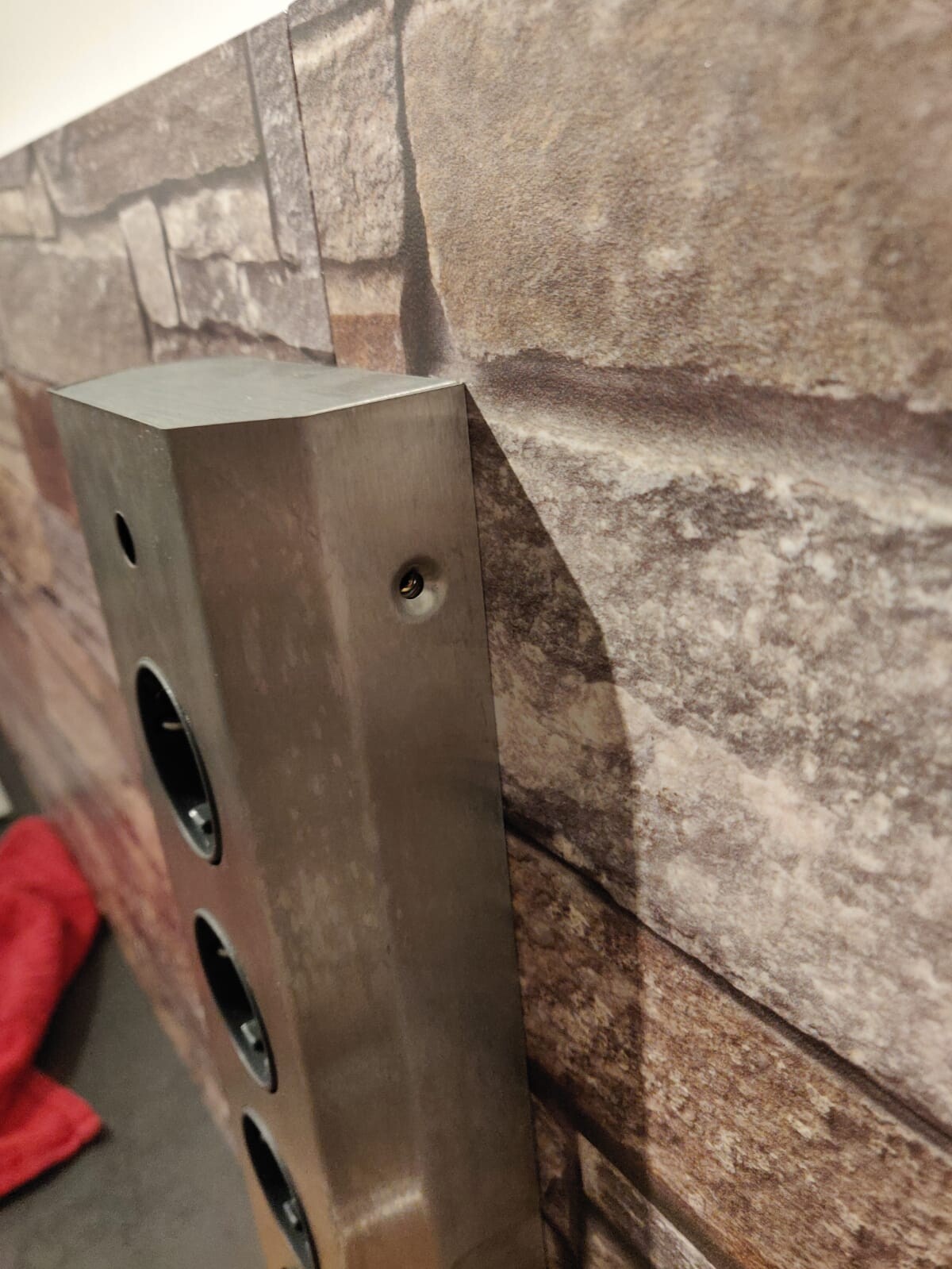 Metallischer Wand-Dosenkasten mit runden Öffnungen an Steinwand montiert