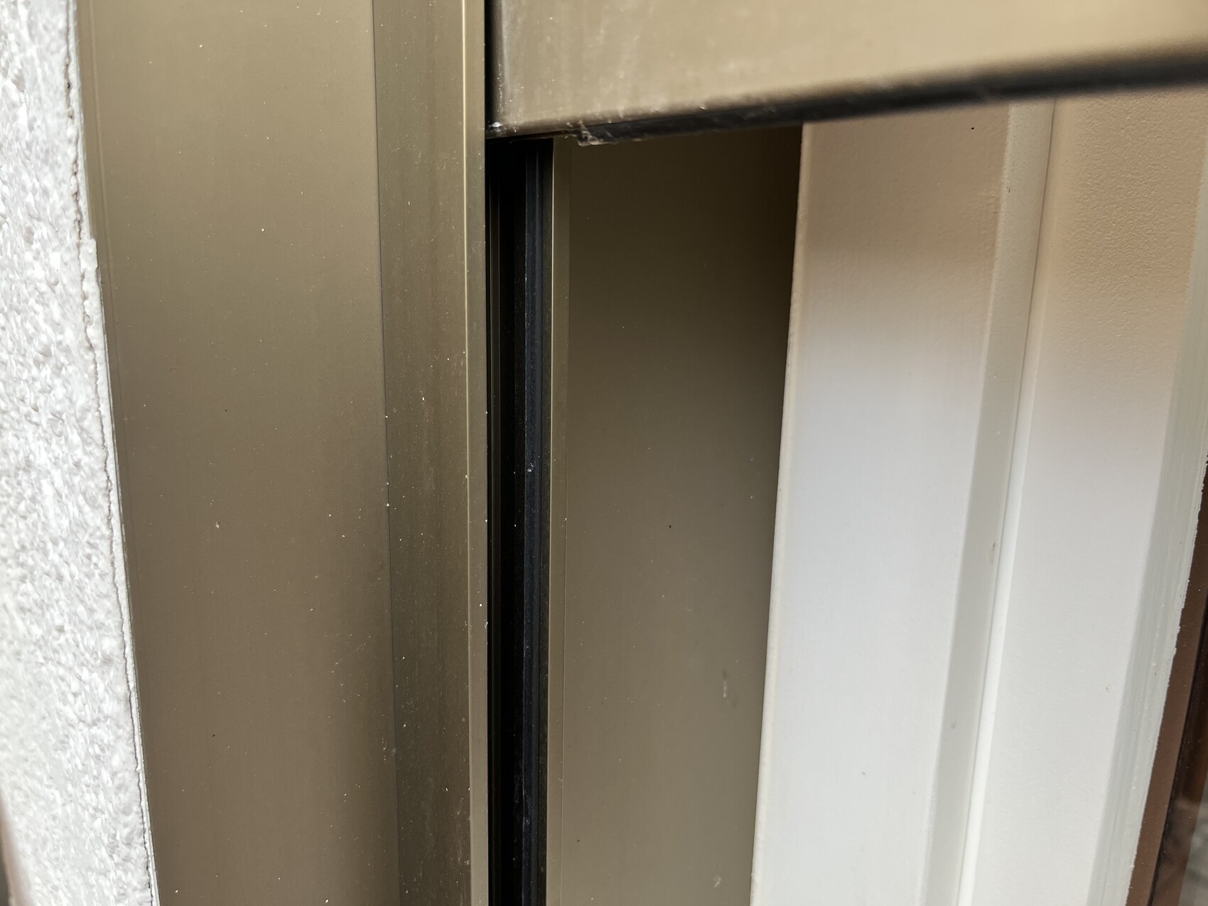 Nahaufnahme eines braunen Tür-/Fensterrahmens mit offener Spalte und dunklem Innenraum