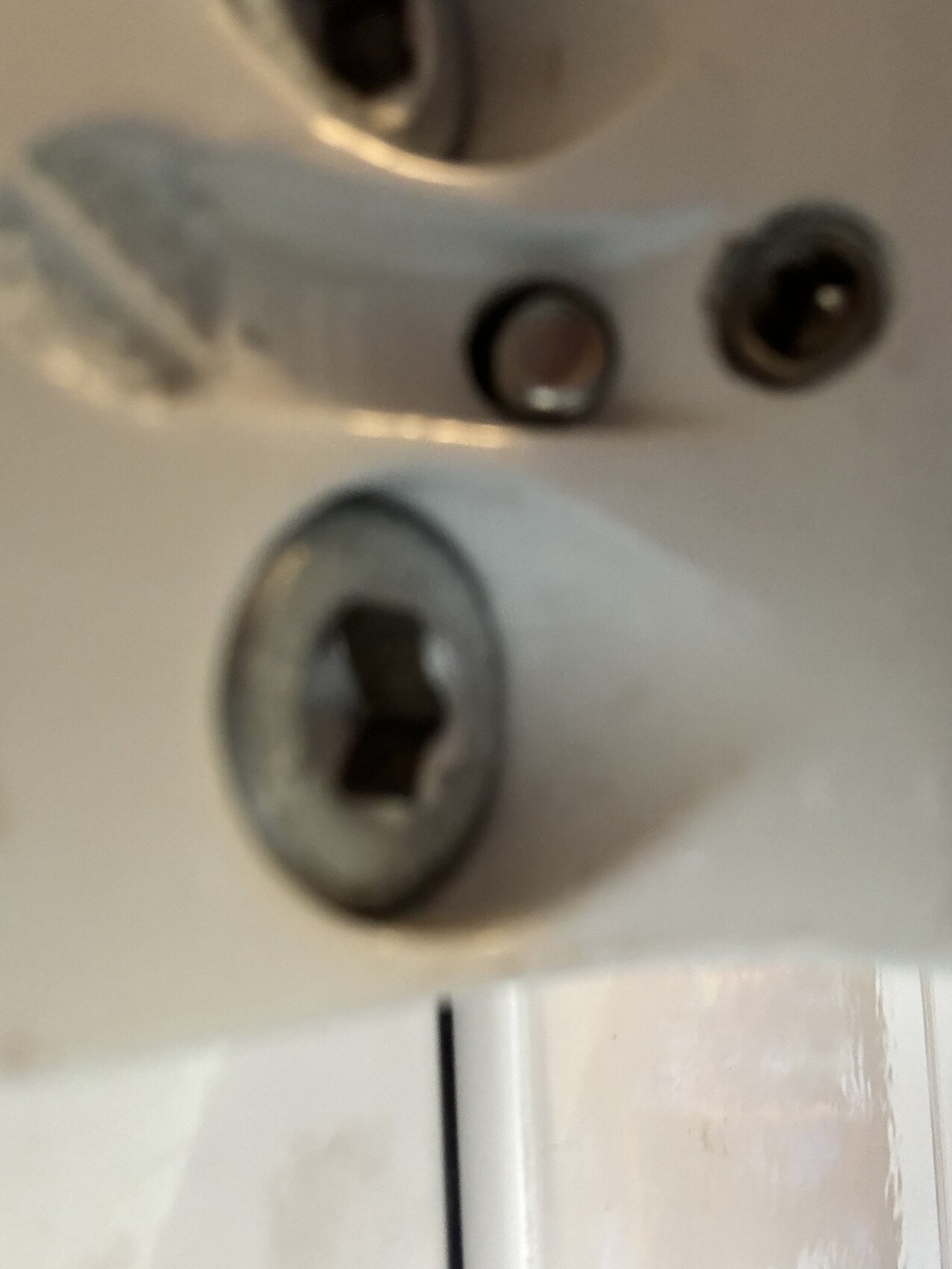 Nahaufnahme eines Türschlosses mit Schrauben am Türrahmen, unscharf