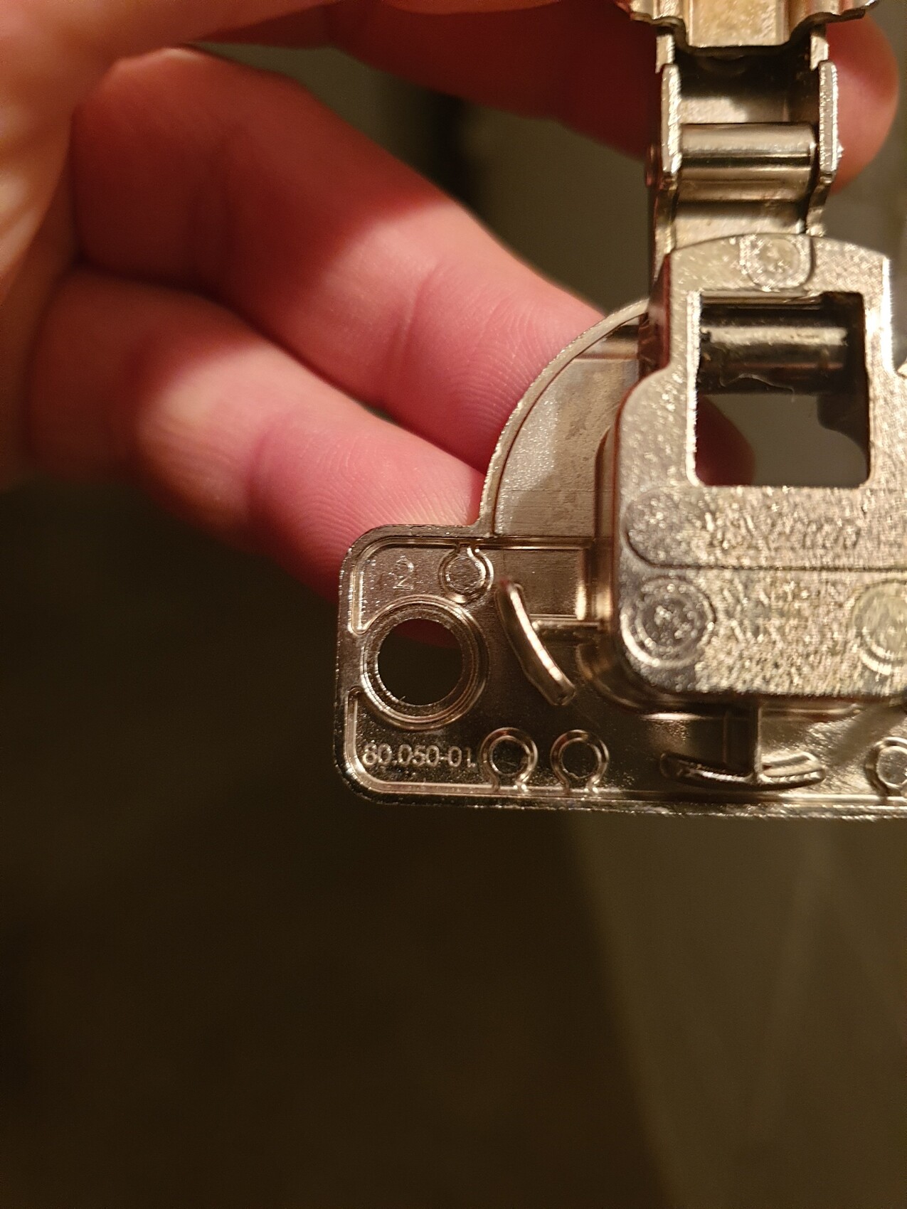 Nahaufnahme eines metallischen Mechanismus mit Federteil, von Fingern gehalten.